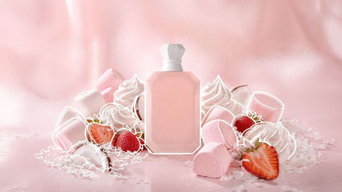 Pink perfume bottle surrounded by strawberries, marshmallows, whipped cream, coconut, and pink sweets against a soft pink background.