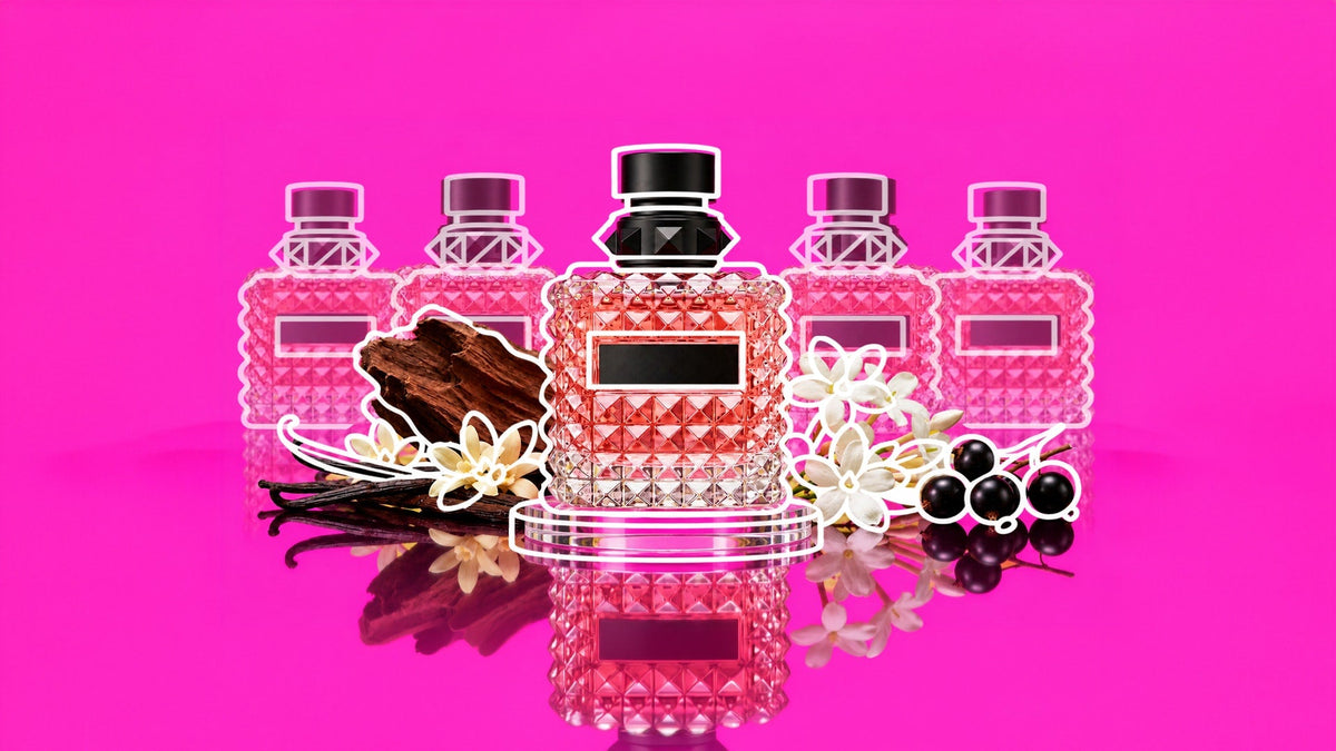 Faceted pink perfume bottle with a black cap, surrounded by four outlined perfume bottles, vanilla pods, white flowers, dark berries, and wood against a vibrant pink background with a reflective surface.