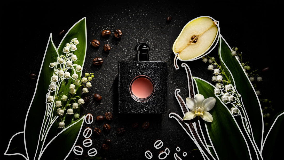 Black perfume bottle centered on a dark background, surrounded by lily-of-the-valley flowers, green leaves, coffee beans, vanilla pods, a white blossom, and a halved pear, with decorative white line-art accents suggesting fragrance notes.
